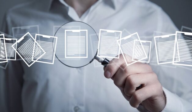 Man holding magnifying glass with a documents.